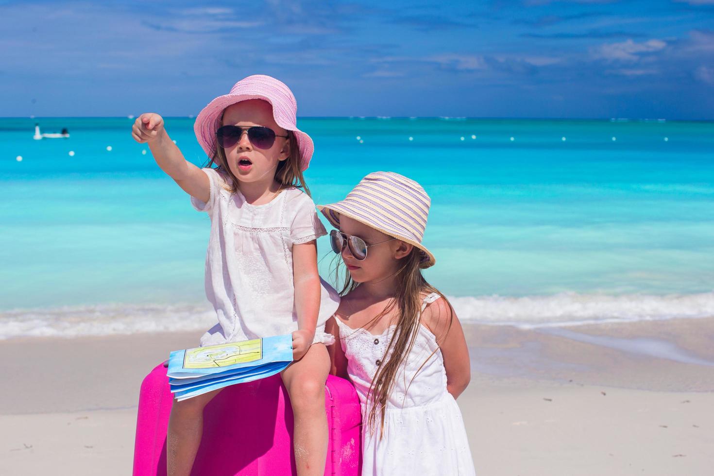 Schwestern mit Karte und Koffer am Strand foto