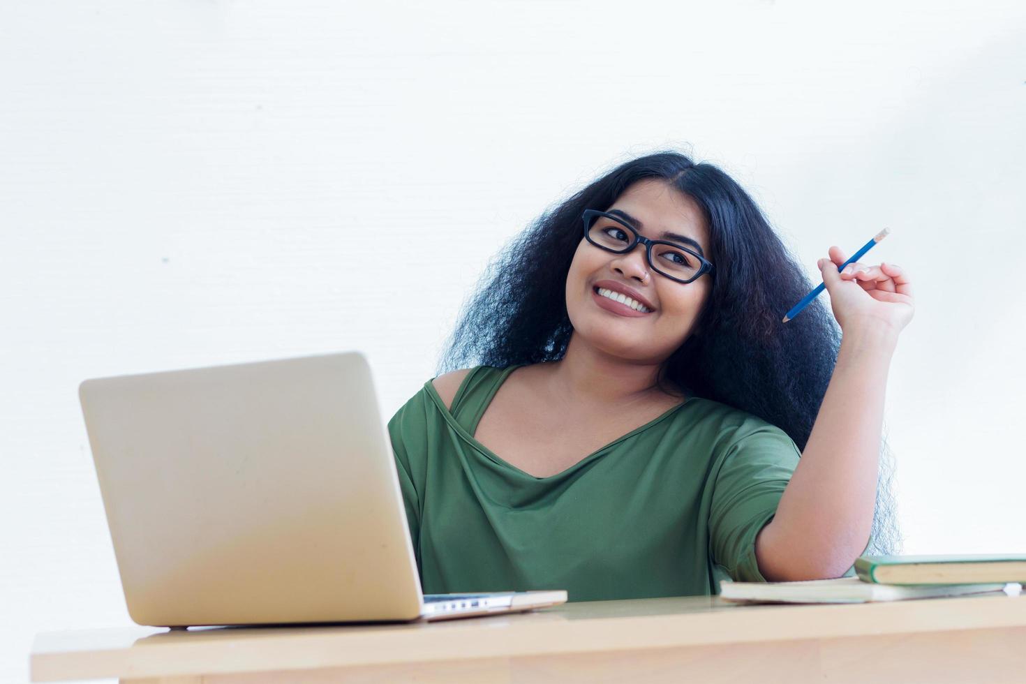 lächelnde Frau, die an ihrem Laptop arbeitet foto