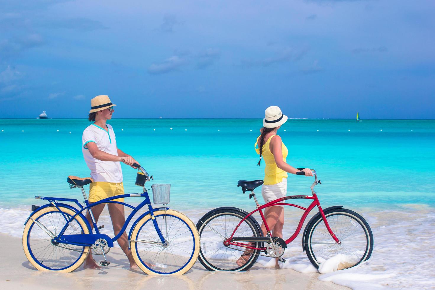Paar mit Fahrrädern an einem weißen Sandstrand foto