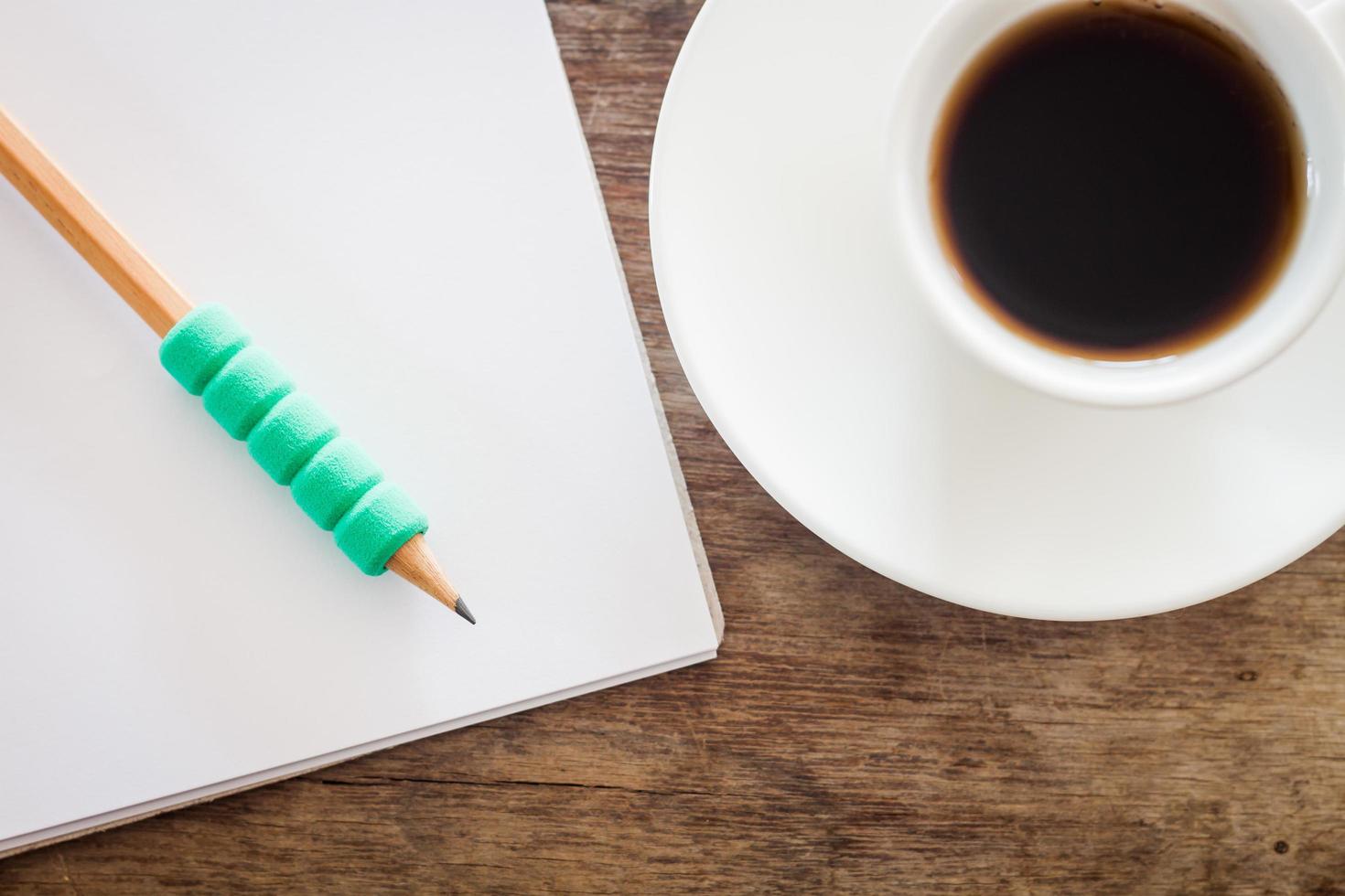 Bleistift auf einem Notizbuch mit einer Kaffeetasse foto