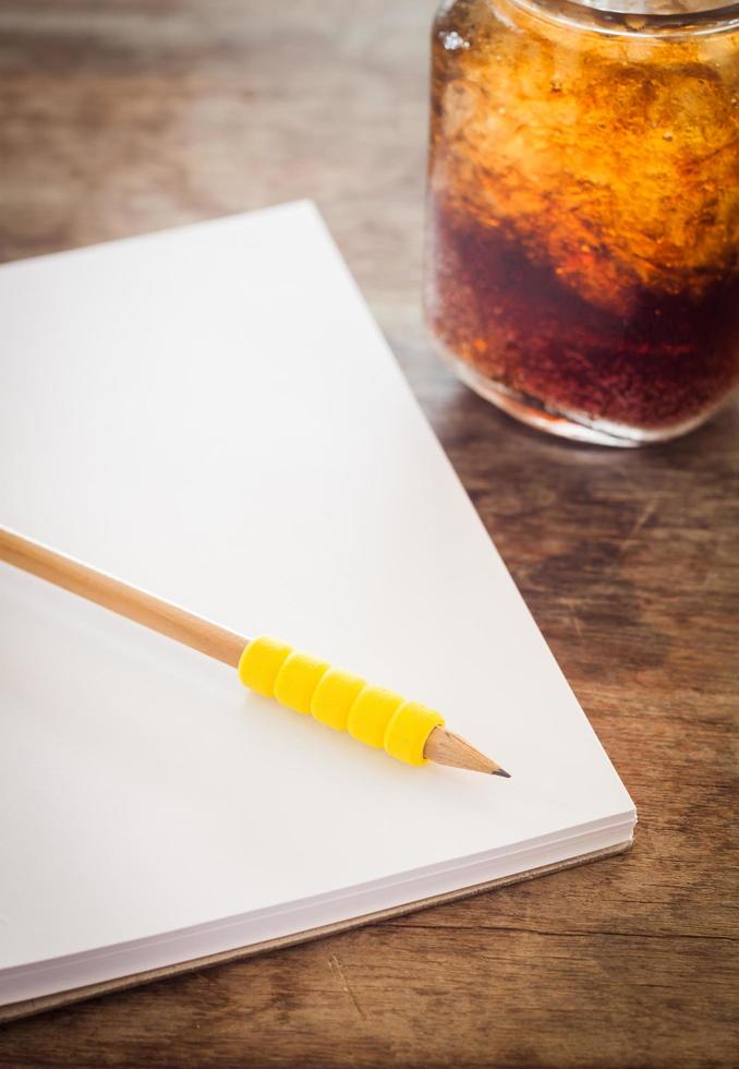 Bleistift auf einem offenen Notizbuch mit einem Soda foto