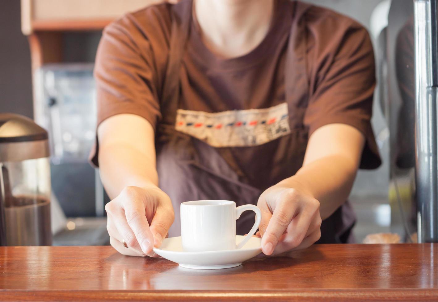 Barista bietet eine weiße Tasse Kaffee an foto