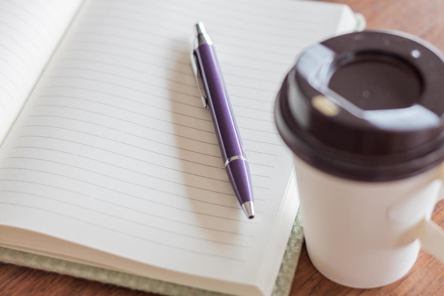 Stift und Notizbuch mit einer Kaffeetasse foto