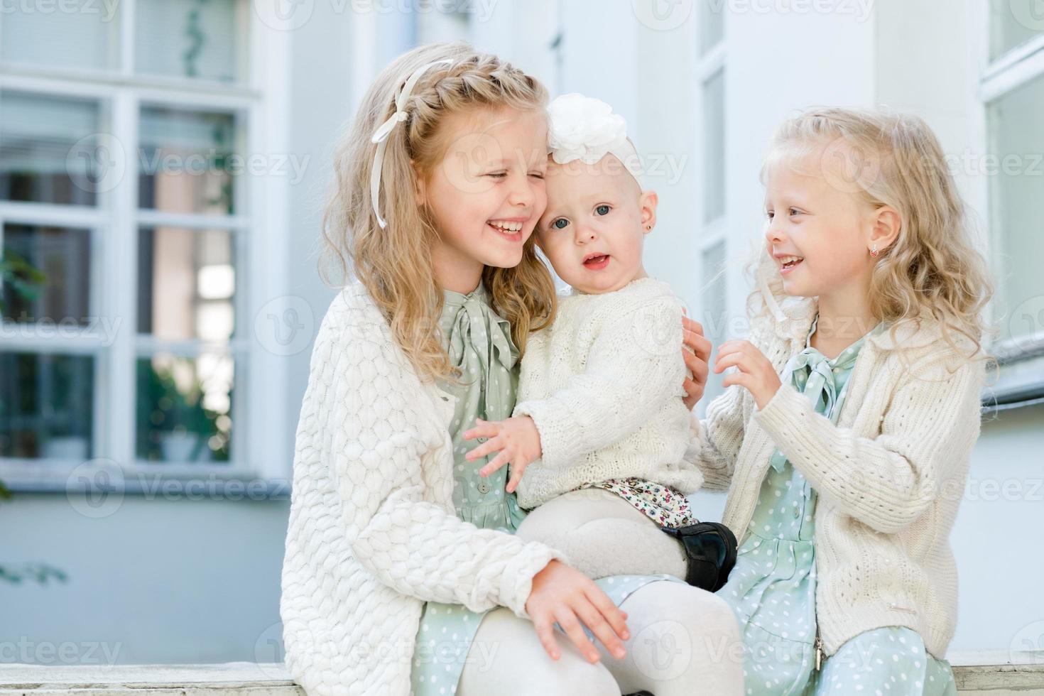 3 kleine Mädchen mit hellem Haar umarmen sich. Liebe der Schwestern foto