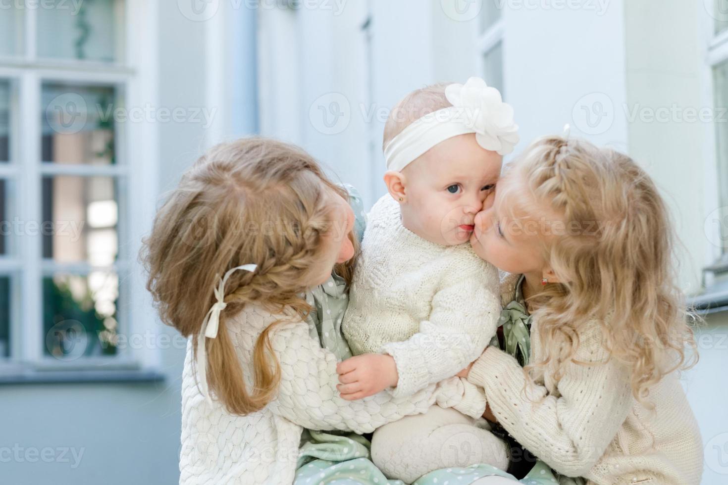 3 kleine Mädchen mit hellem Haar umarmen sich. Liebe der Schwestern foto