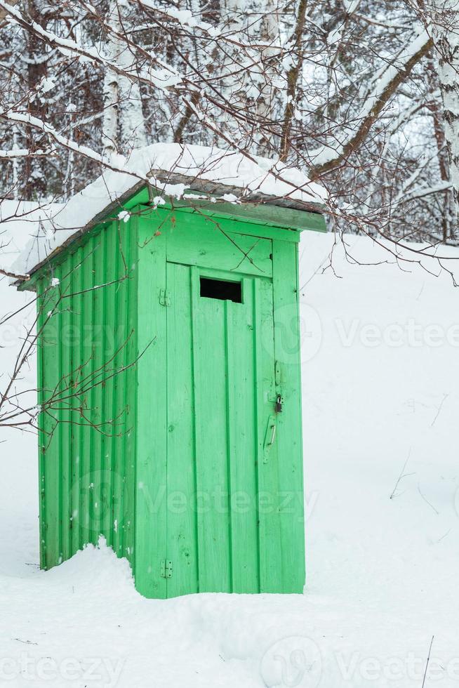 rustikale Holztoilette im Freien in einem verschneiten Wald foto