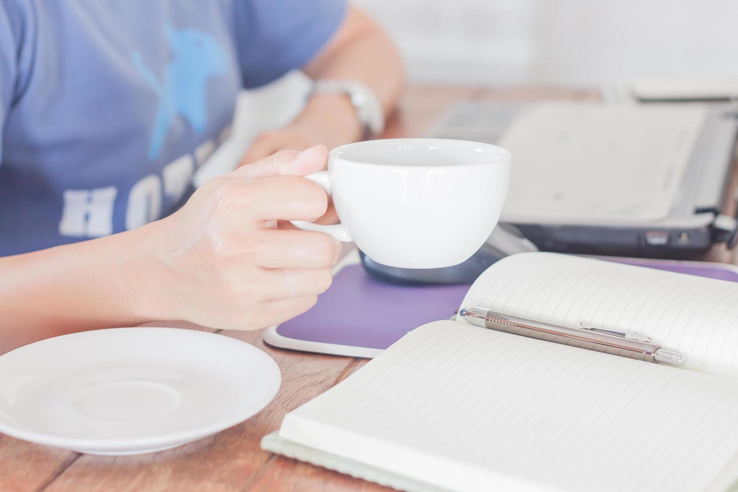 Person, die beim Kaffeetrinken arbeitet foto