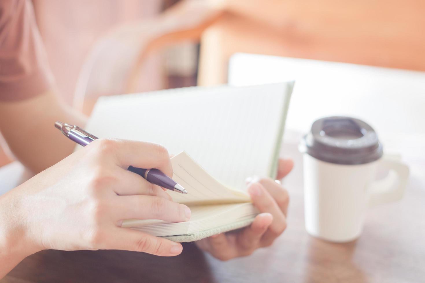 Person, die ein Notizbuch und einen Stift hält foto