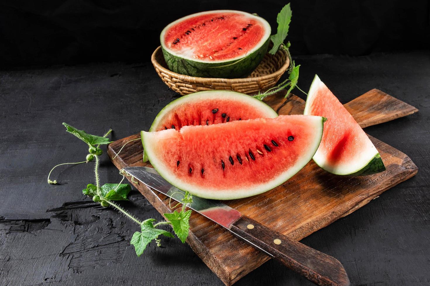 Wassermelonenscheiben auf einem hölzernen Schneidebrett halbieren foto