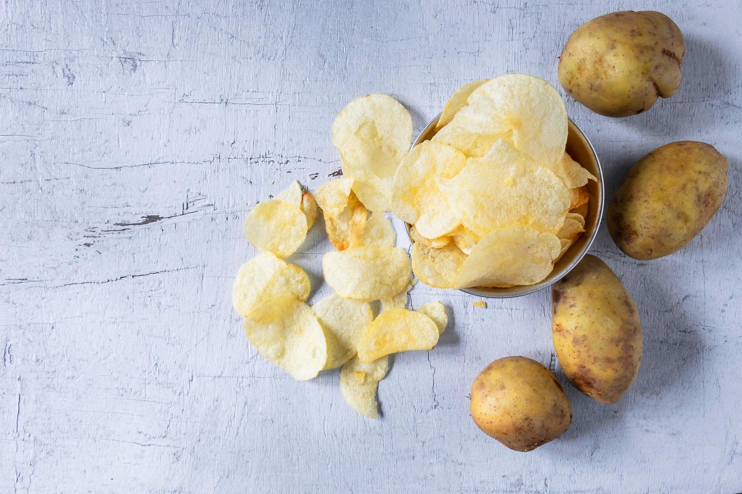 Bratkartoffelchips und rohe Kartoffel in einer Schüssel foto