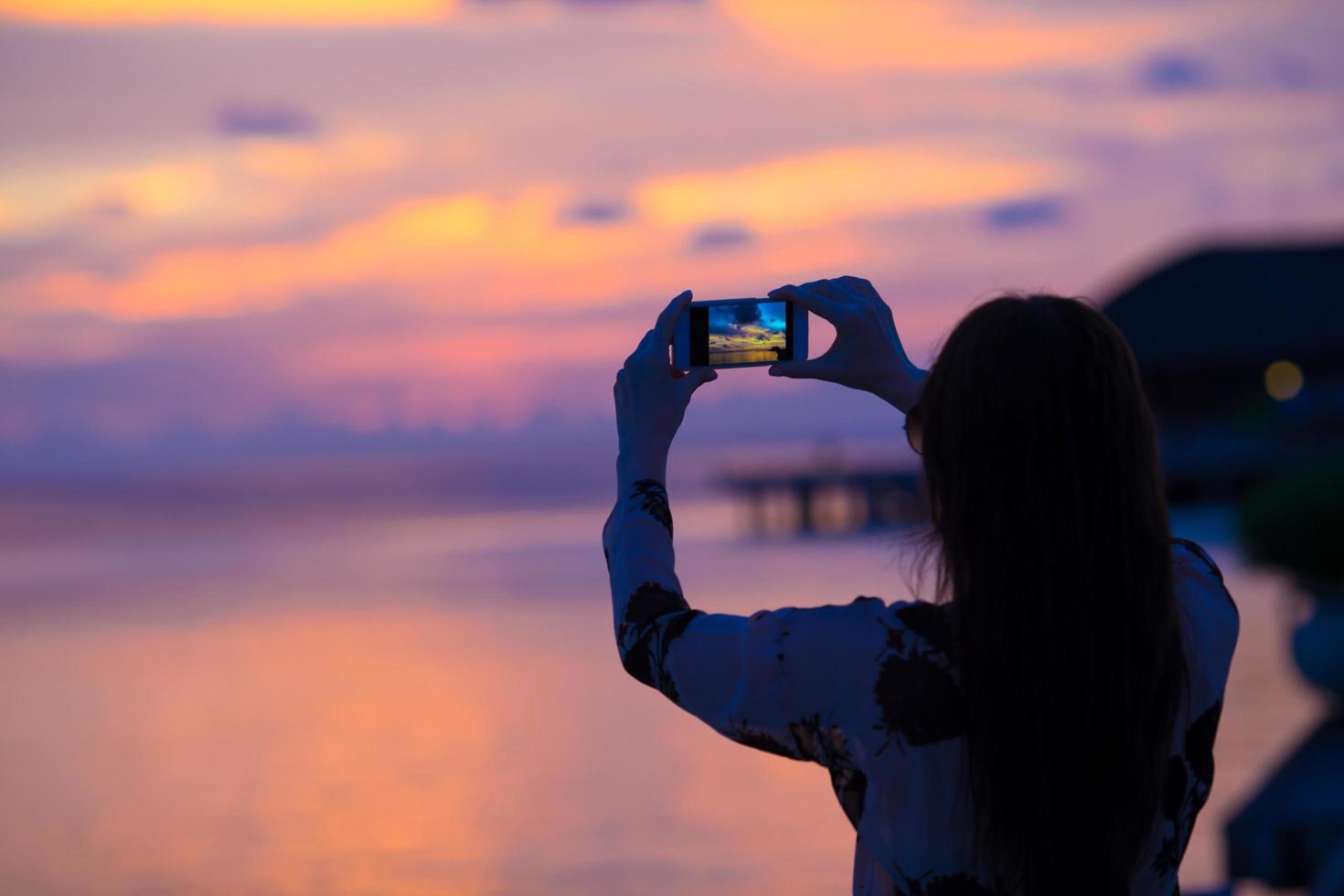 Frau, die ein Foto eines Sonnenuntergangs macht