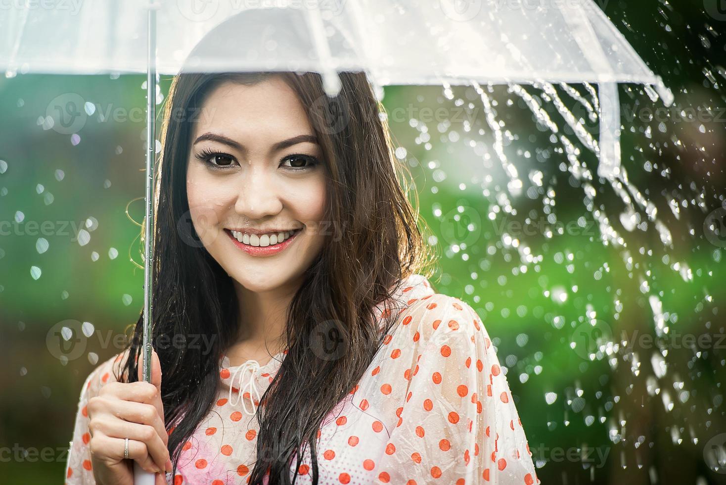 schönes Mädchen im Regen mit transparentem Regenschirm foto