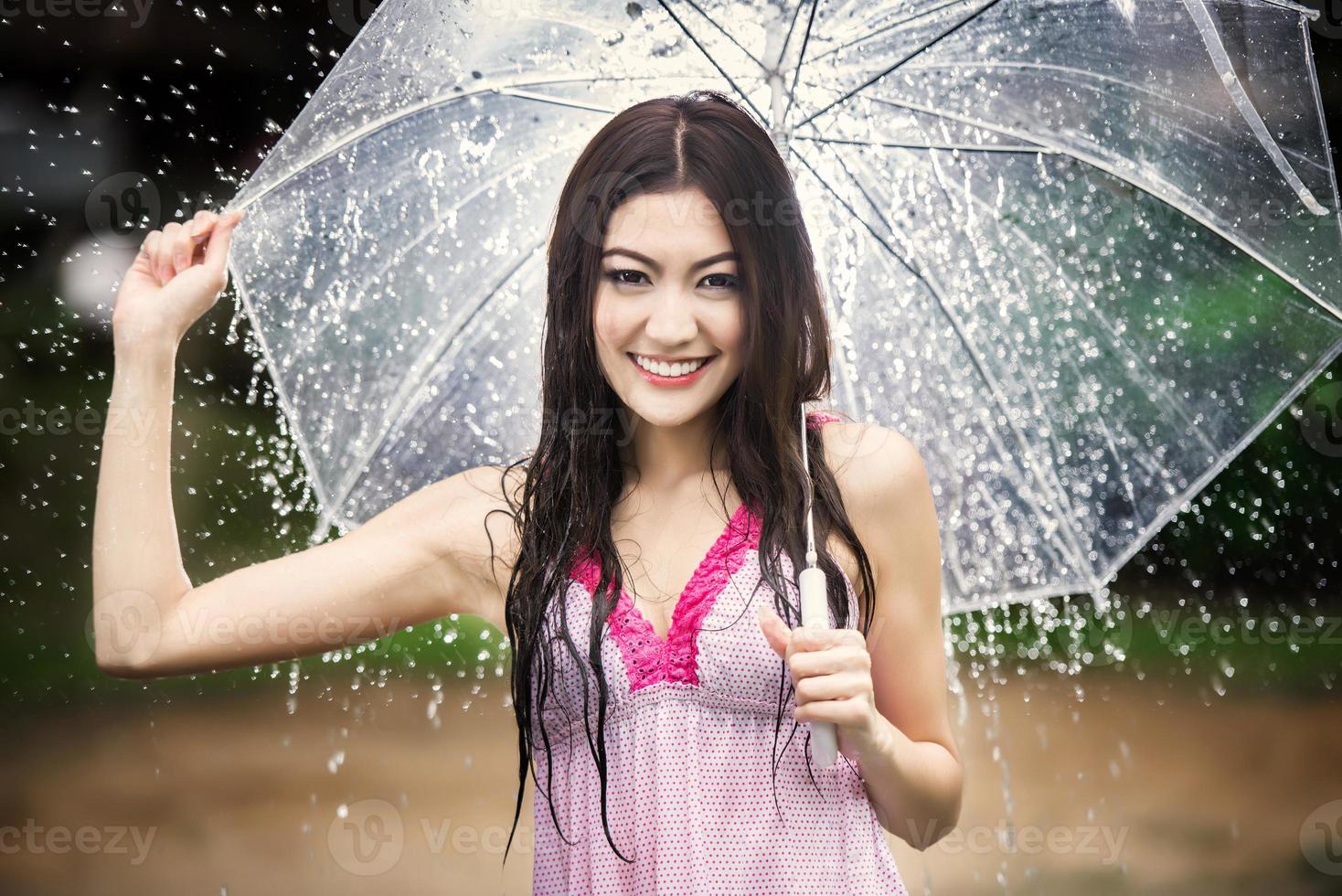 schönes Mädchen im Regen mit transparentem Regenschirm foto