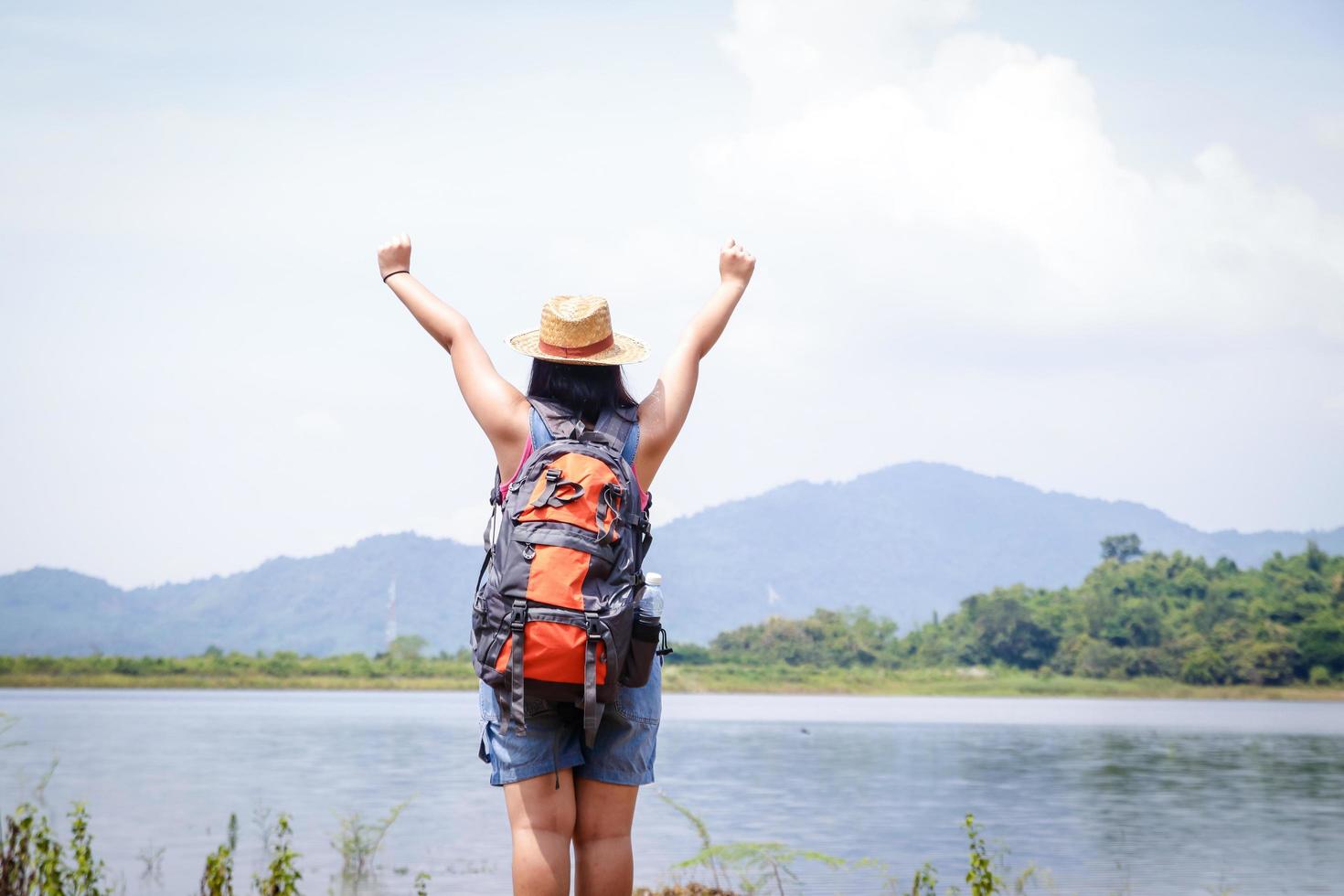 eine asiatische Frau, die einen Wanderrucksack trägt. sie hebt die Arme. fühle mich lustig und glücklich. Geschäftskonzept für Naturtourismus foto