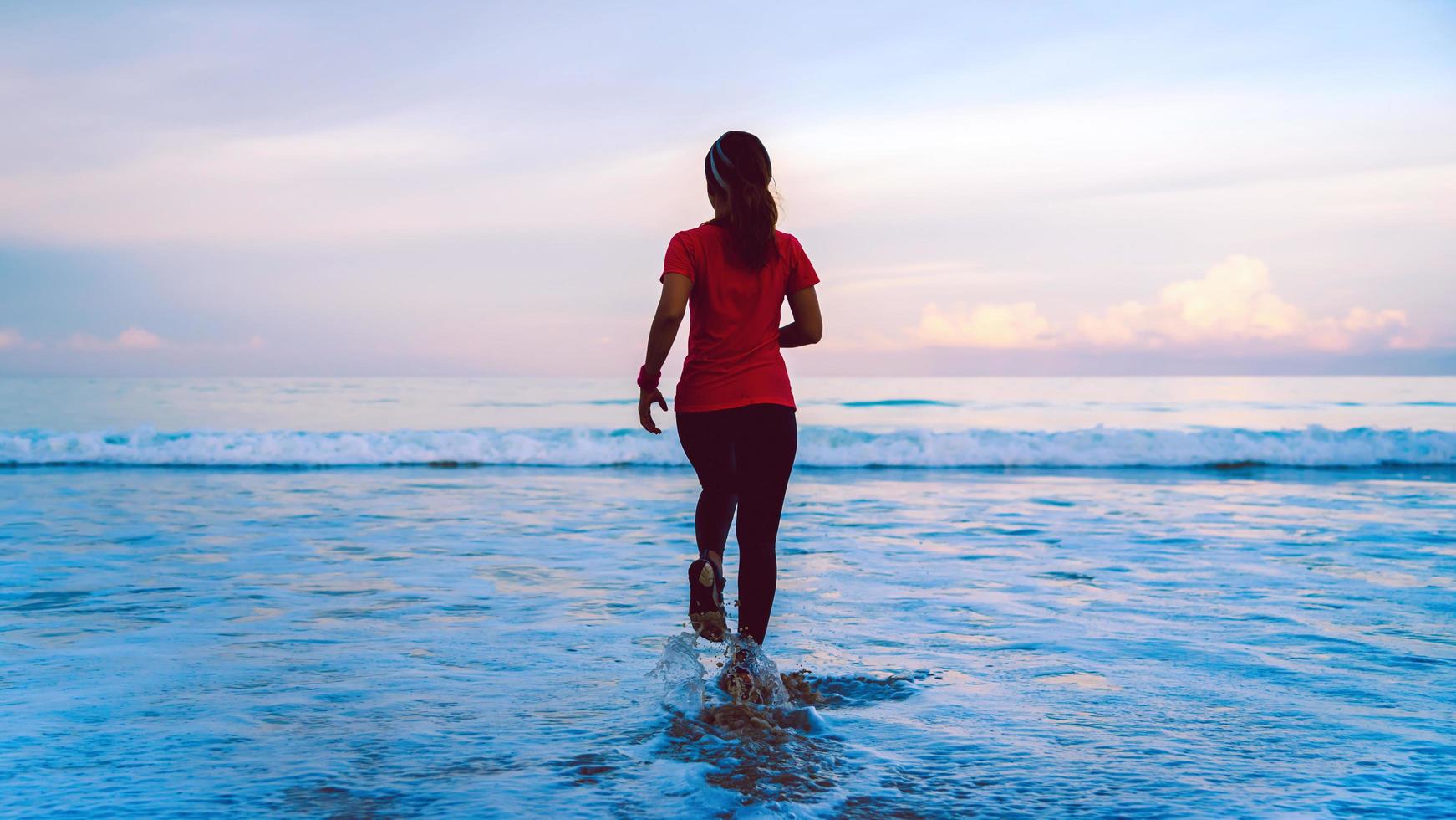 Mädchen, das morgens am Strand joggt. entspannen und glücklich mit dem Laufen auf dem Meer. im Sommer foto