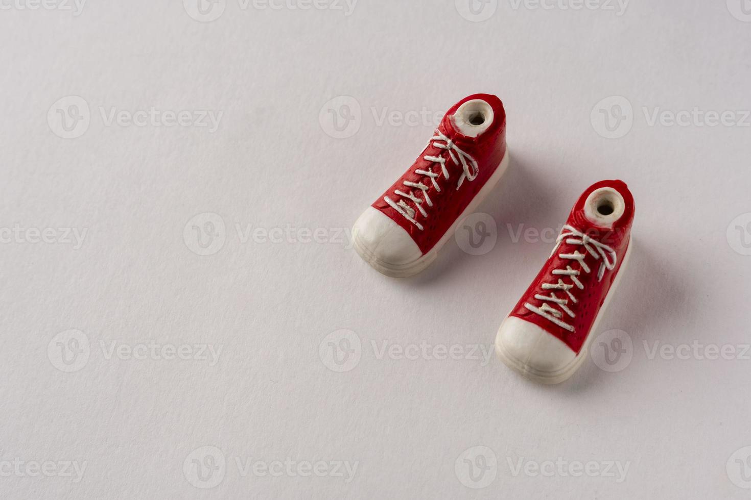 ein paar rote schuhe turnschuhe auf weißem hintergrund, kreative komposition. Spielzeug Turnschuhe auf weißem Hintergrund foto