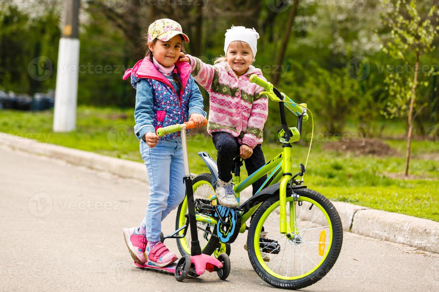 glückliche Freundin fährt Rollschuhe, Roller und Fahrrad im Schlepptau und lacht glücklich foto