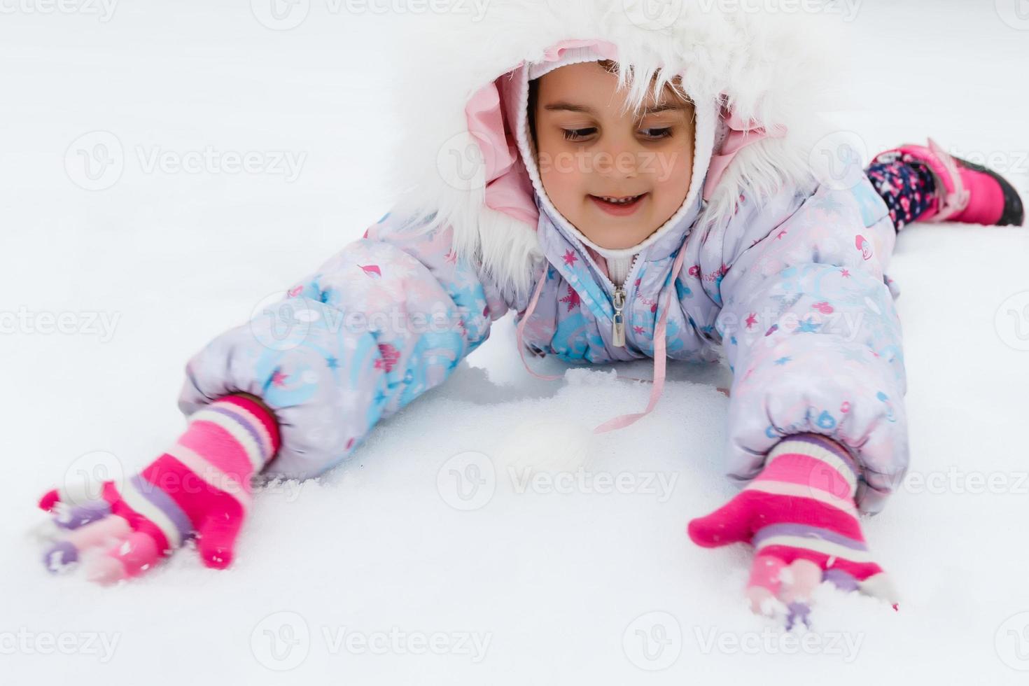 Porträt eines kleinen Mädchens, das im Schnee lächelt foto