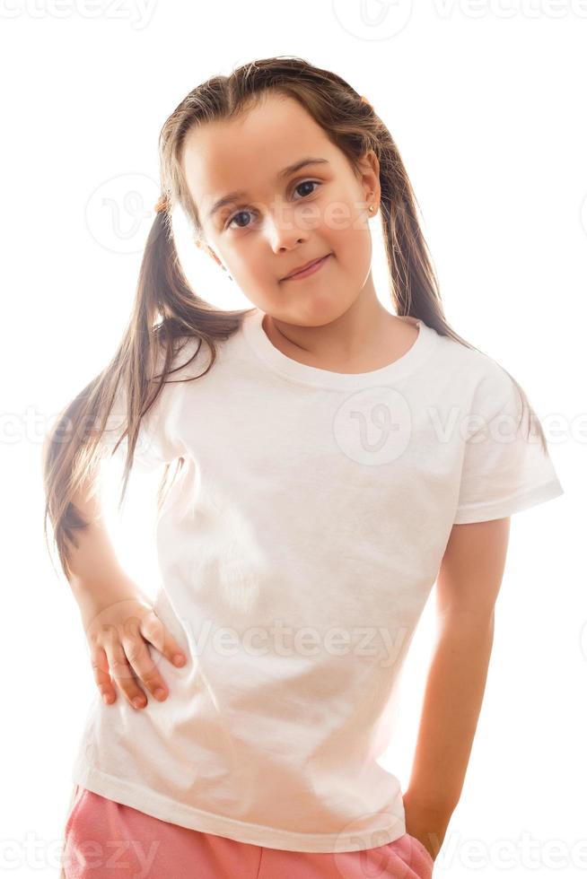 Positives kleines Mädchen im lässigen weißen T-Shirt zeigt eine Leerstelle für Logo-Design an foto