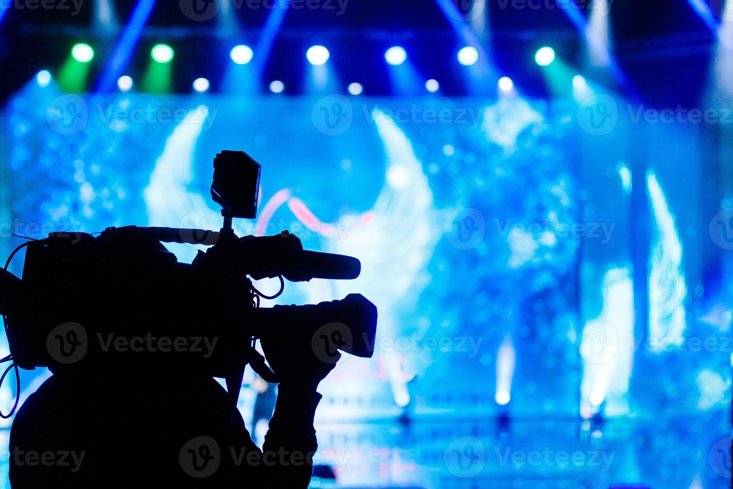 Professioneller Videokameramann, der mit seiner Ausrüstung arbeitet, blauer Hintergrund foto