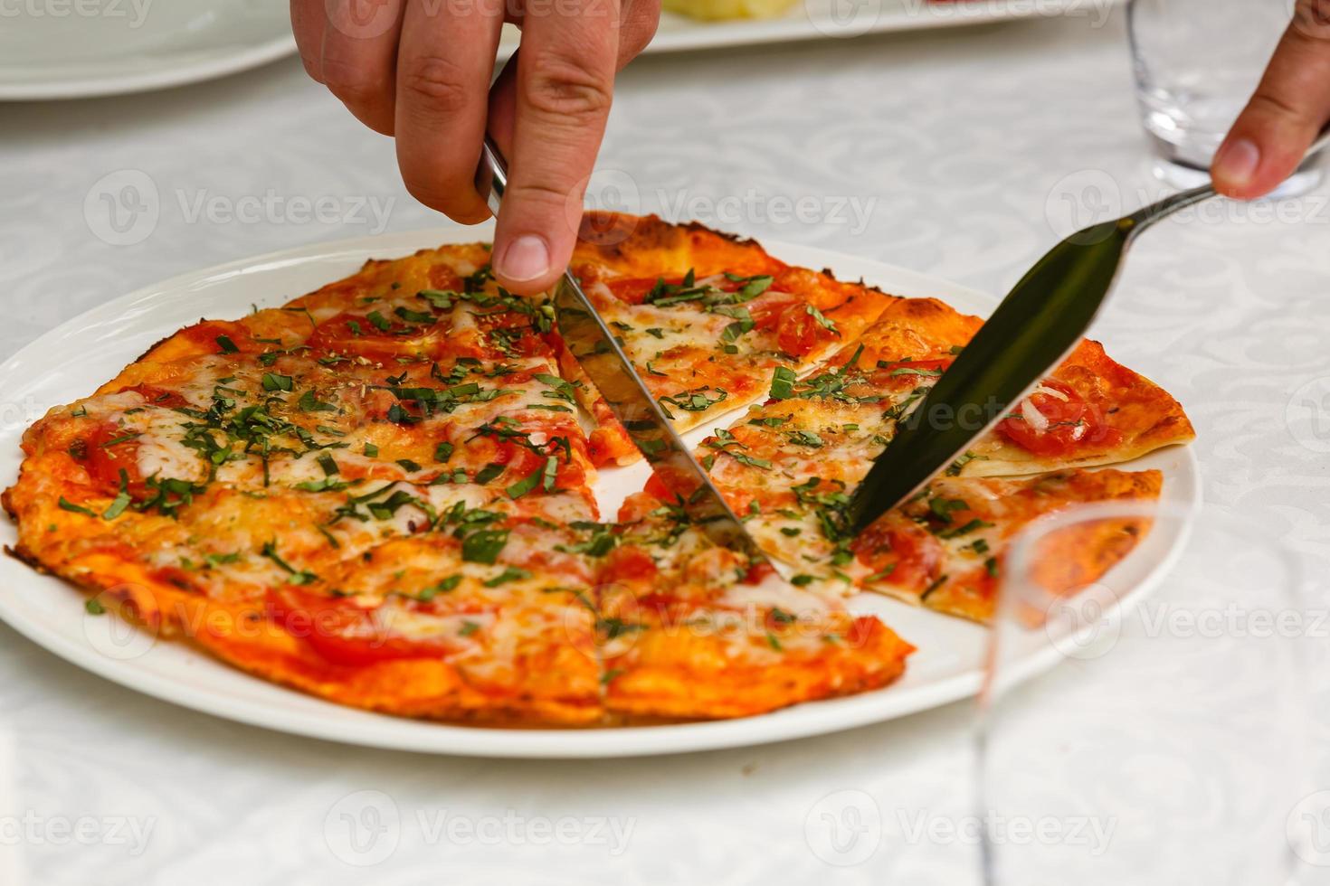 flachgelegt. Nahaufnahme von Menschenhänden, die Scheiben Peperoni-Pizza vom Holzbrett nehmen. tisch serviert mit schwarzer textilserviette. Smartphone auf dem Tisch. leute essen fast food im café. foto