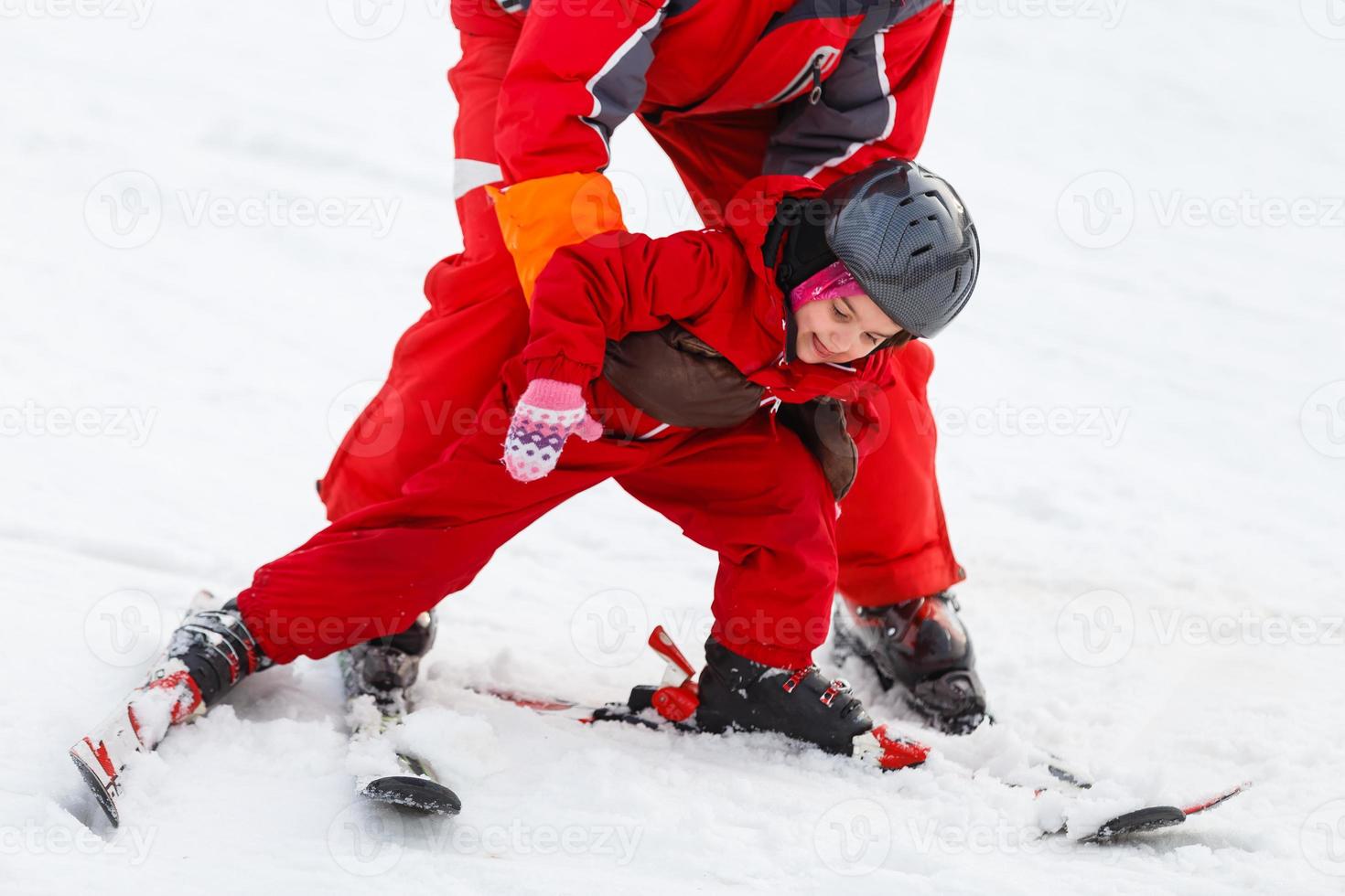 Mädchen lernt Skifahren nach einem Sturz aufstehen sie gleitet langsam auf Skiern im weichen Neuschnee foto