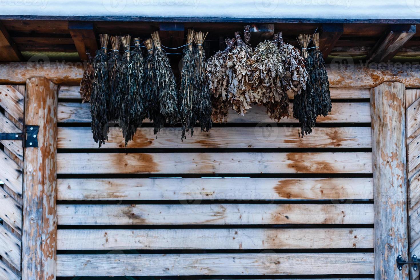 Die Birkenbesen für ein traditionelles Dampfbad hängen an einer Holzwand foto