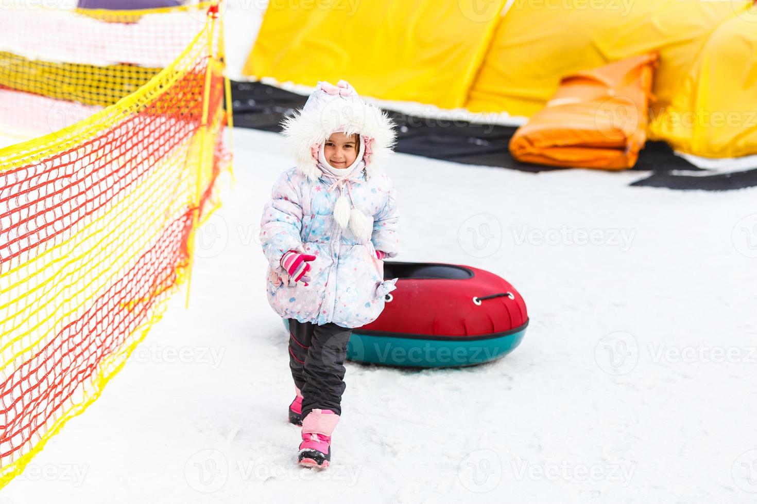 kleines Mädchen mit Snowtube bereit zum Rodeln einen Hügel hinunter foto