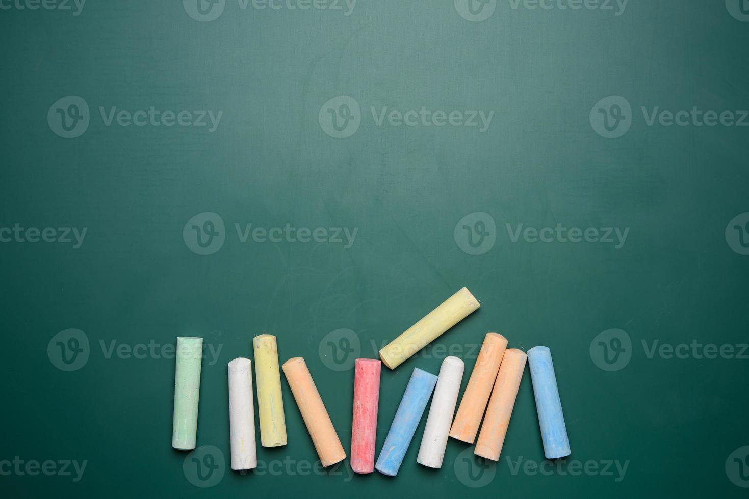 Mehrfarbige Buntstifte auf dem Hintergrund der Schultafel mit grüner Kreide foto