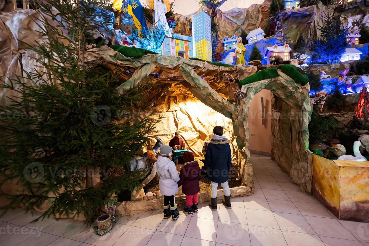 Rückseite von drei Kindern, die in der Weihnachtskrippe in der Kirche suchen. foto