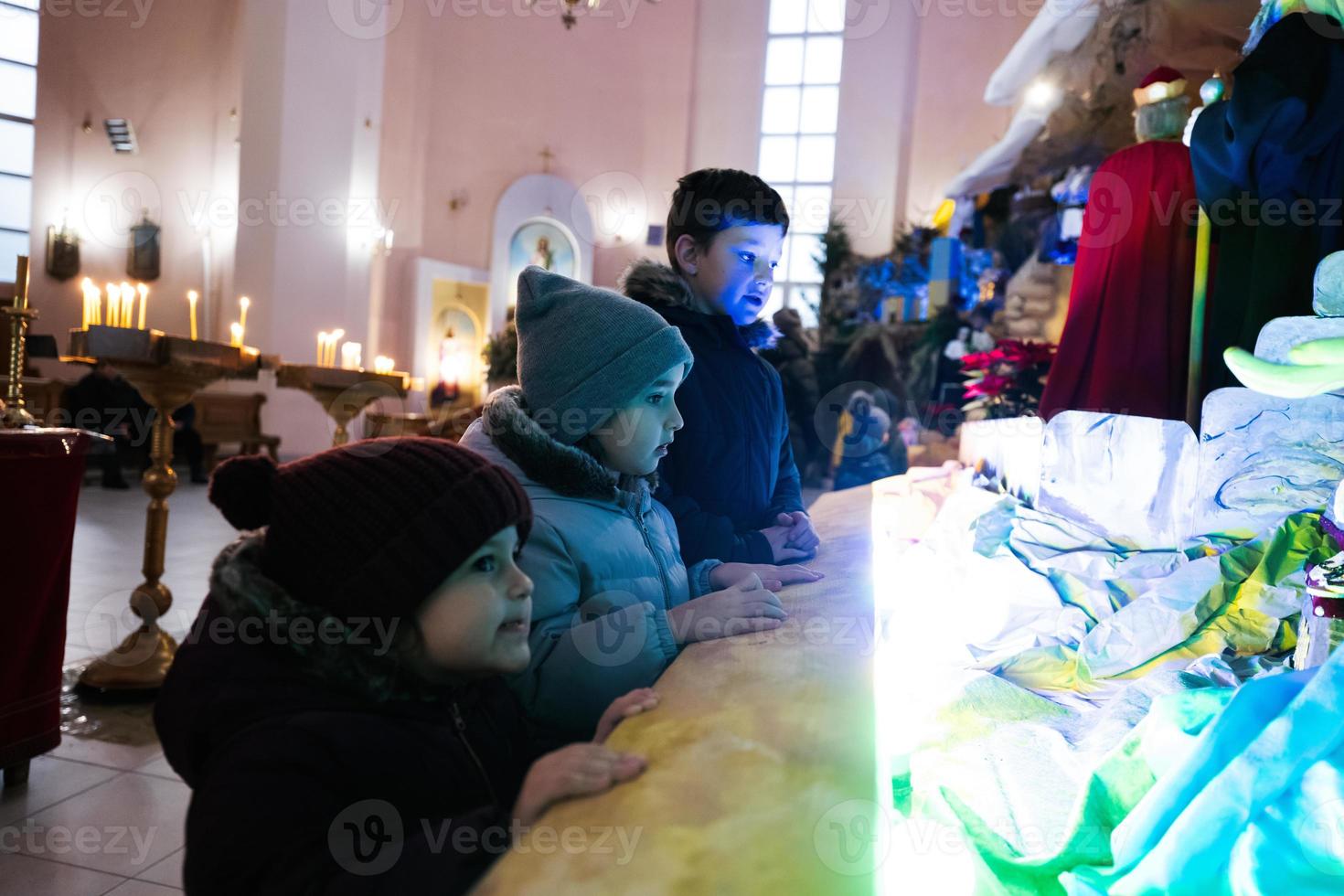 Drei Kinder suchen in der Weihnachtskrippe in der Kirche. foto