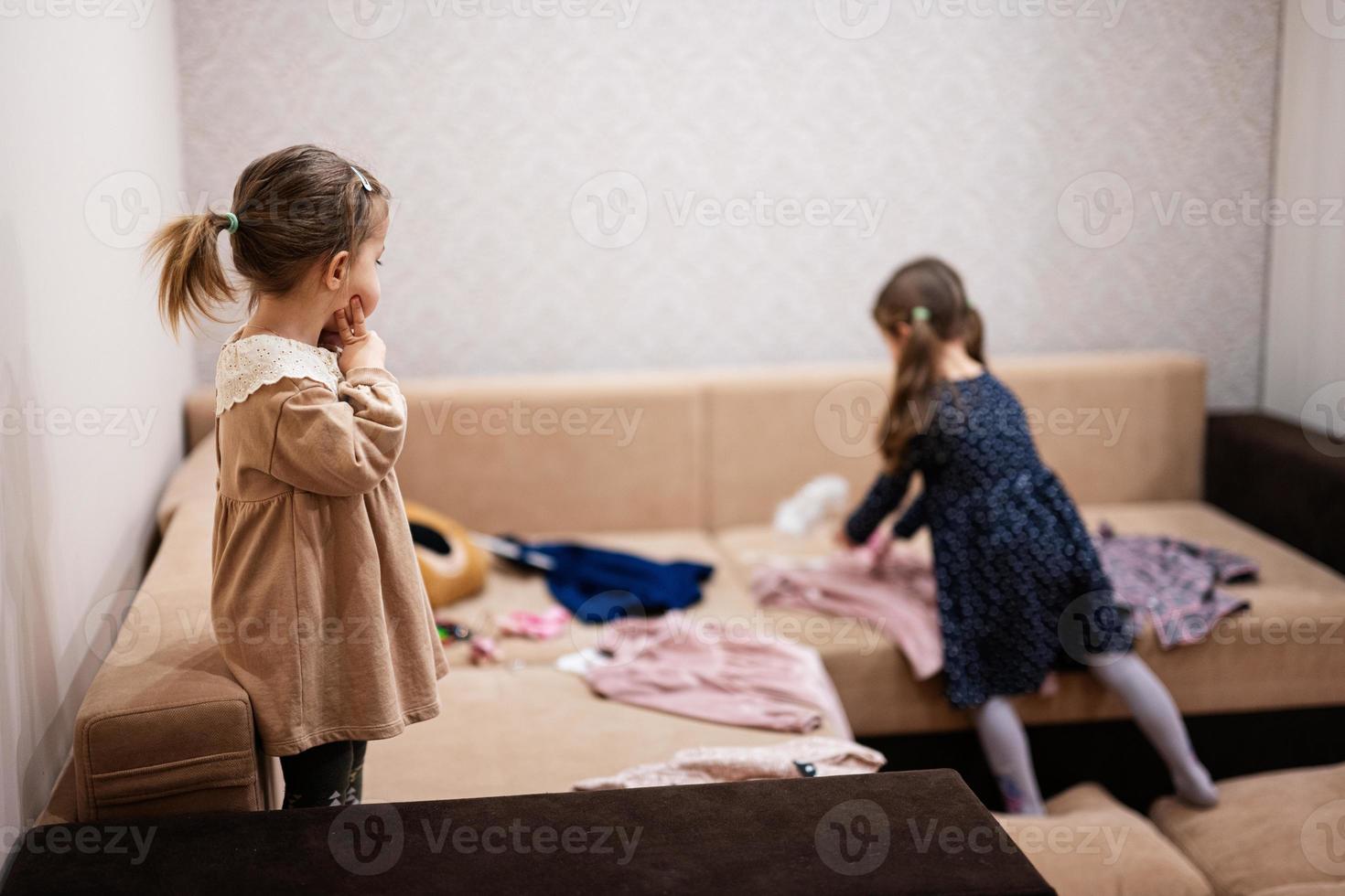 zwei schwestern suchen zu hause auf dem sofa kleider aus dem kleiderschrank aus. foto