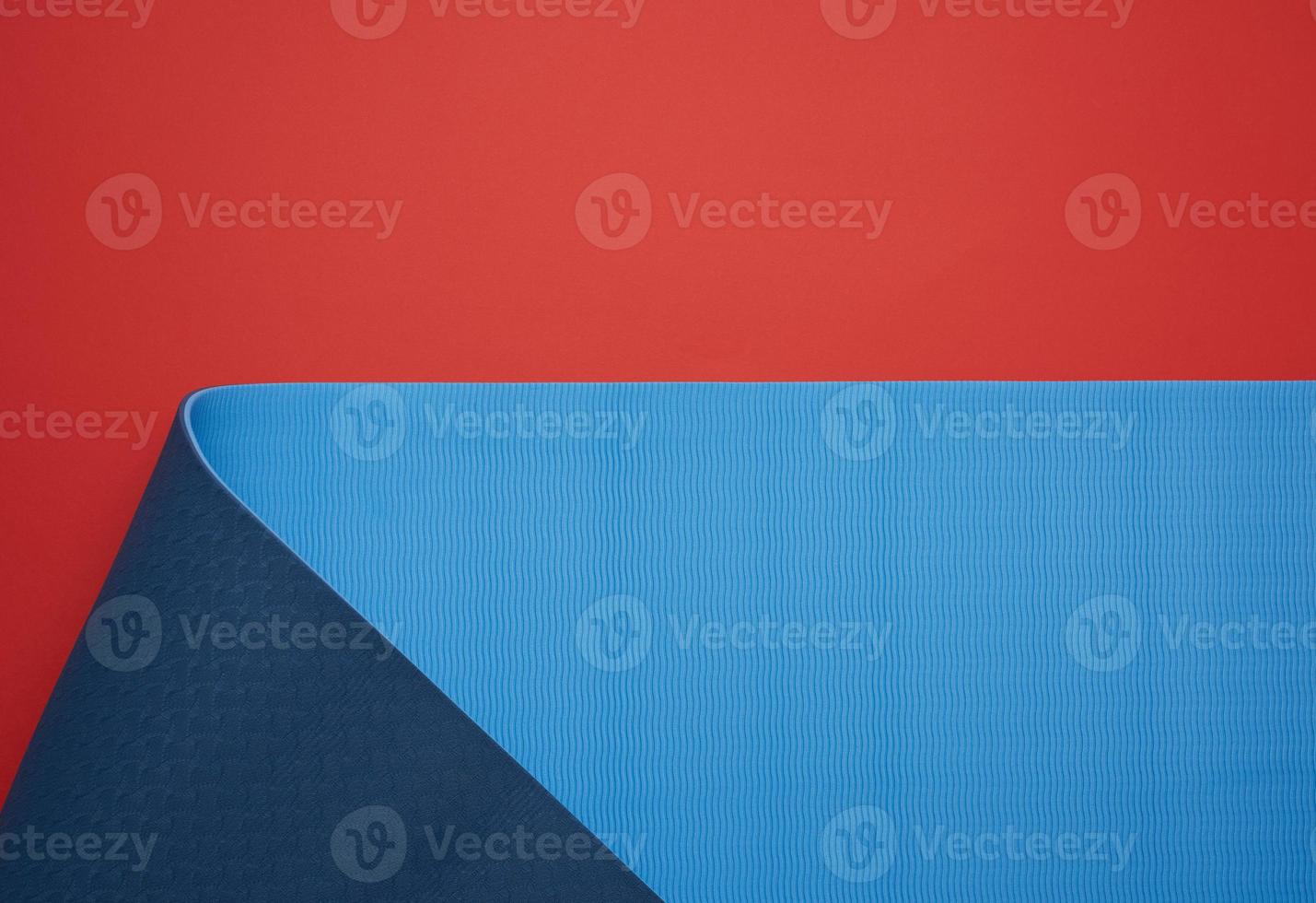 neoprenblau verdrehte matte liegt auf rotem hintergrund, sportgeräte foto