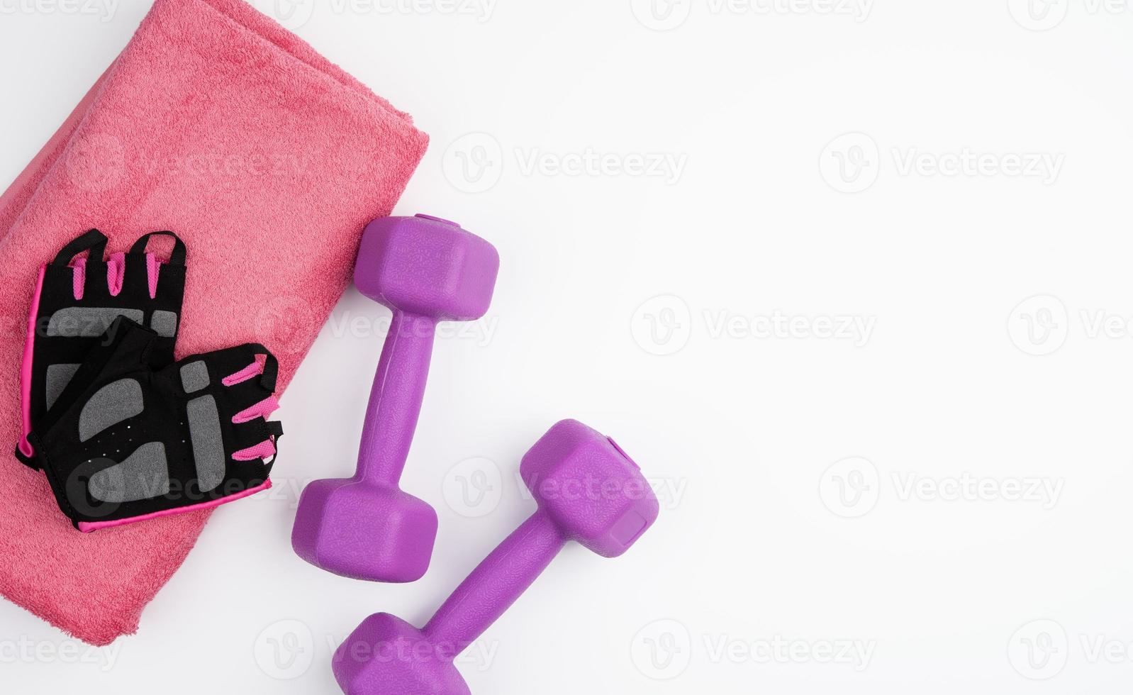 Handschuhe, Paar lila Hanteln und rosa Handtuch auf weißem Hintergrund foto