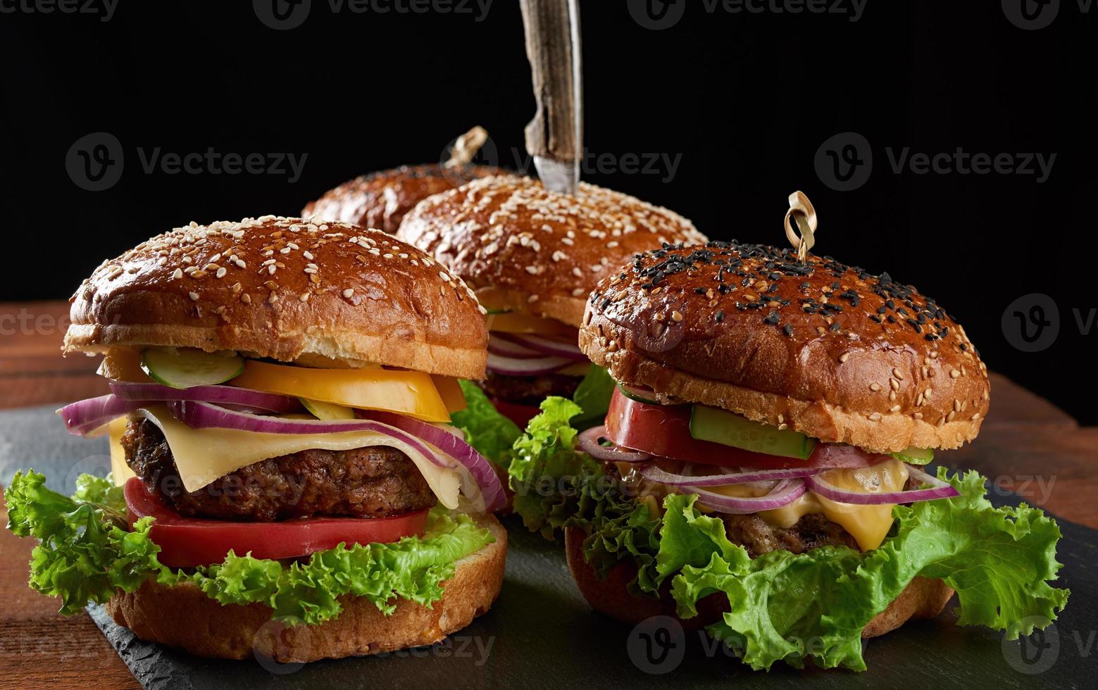 Leckere Burger mit gebratenem Rinderkotelett, Tomate, Salat und Zwiebeln, knuspriges Weißmehlbrötchen mit Sesam foto