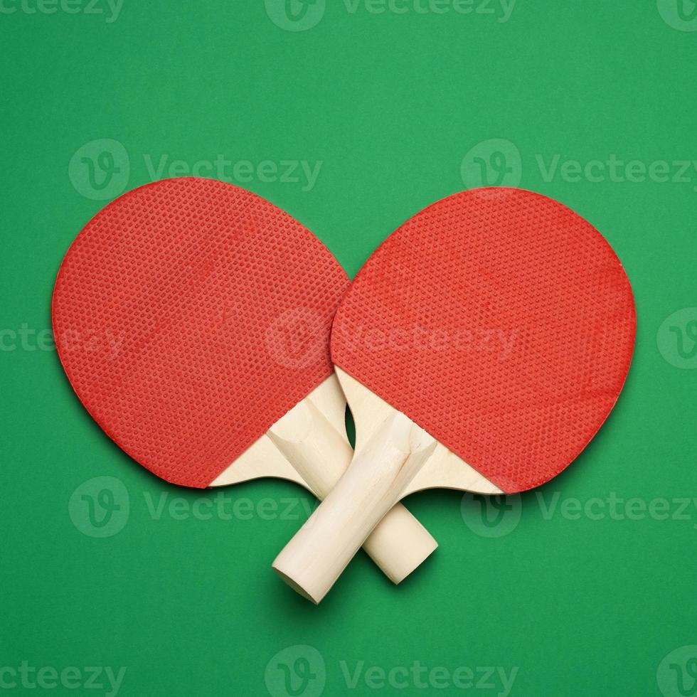 Roter Tischtennisschläger aus Holz auf grünem Hintergrund, Paar Ping-Pong-Sportgeräte foto