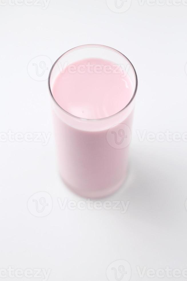 Rosa Milch mit Erdbeergeschmack in einem Glas auf weißem Hintergrund. foto