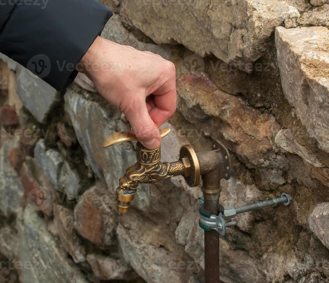 antiker Wasserhahn aus Messing als Baudenkmal. alter Wasserhahn mit Wasser auf der Straße. foto