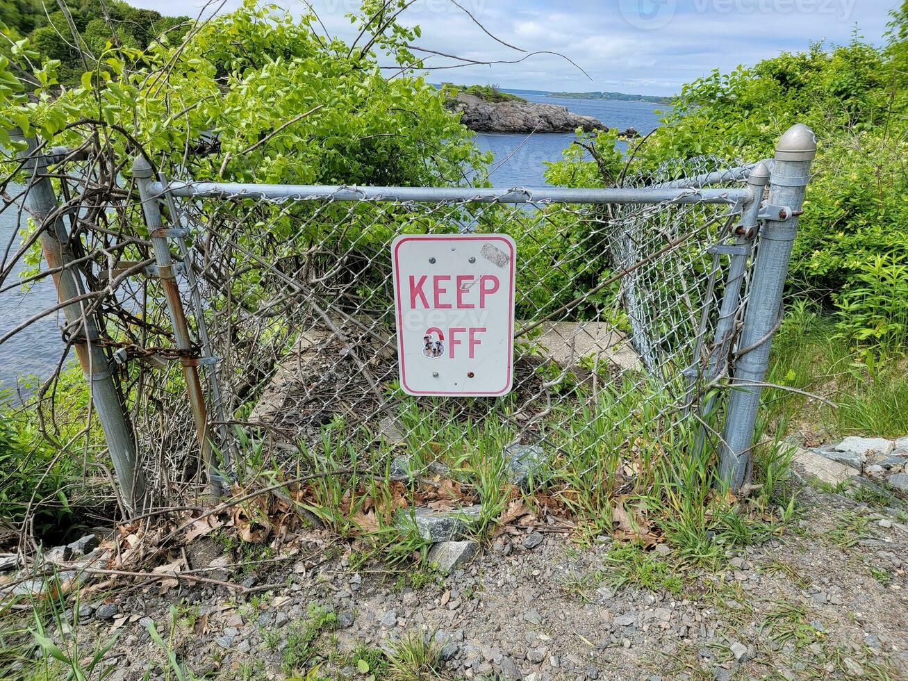 Halten Sie das Schild am Metallzaun in der Nähe von Wasser in der Nähe des Meeres fern foto