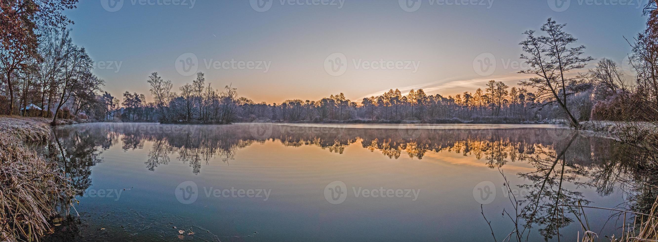 Panoramabild des zugefrorenen Sees bei frostiger Temperatur bei Sonnenaufgang foto