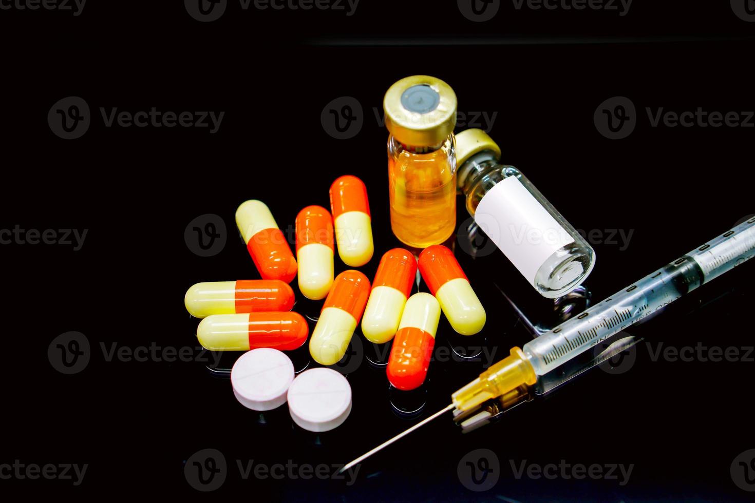 plastikspritze, kapselarzneimittel, injektionsmedikament in fläschchen, weiße und rote pillenmedikamente isolieren auf schwarzem hintergrund. foto