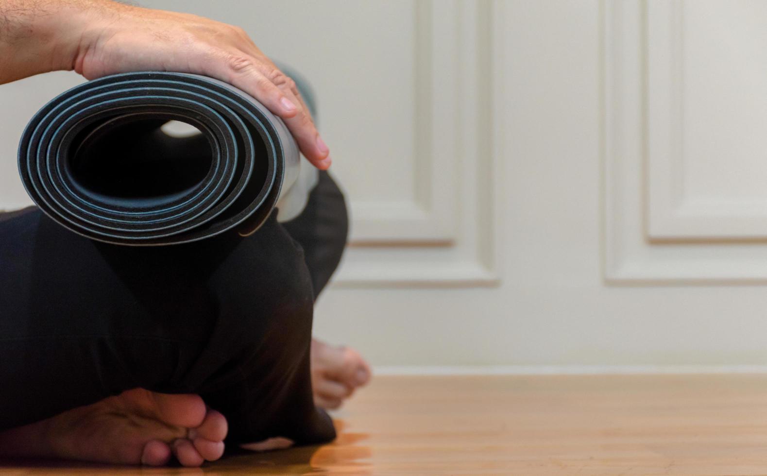 der mann benutzt seine hände, um grünes yoga zu rollen foto