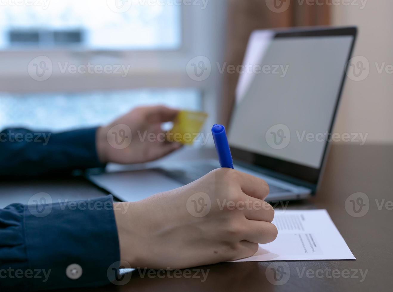 Nahaufnahme der Hand mit Stift zum Schreiben auf Papier, Hand mit Kreditkartenhintergrund mit Tablet, Geschäftskonzept. foto