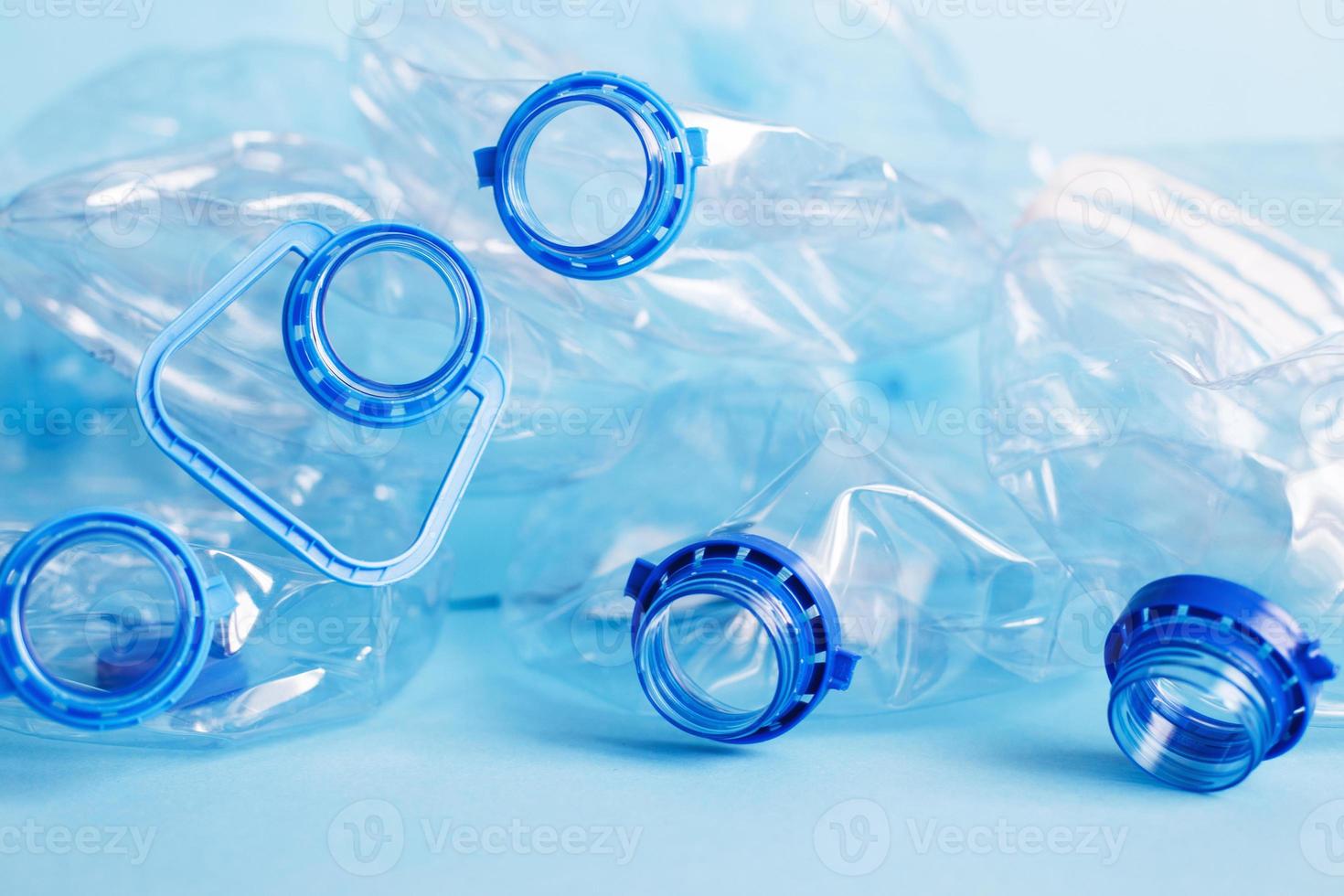 Viele leere, zerknitterte gebrauchte Plastikflaschen auf blauem Hintergrund. abfall- und verschmutzungskonzept foto