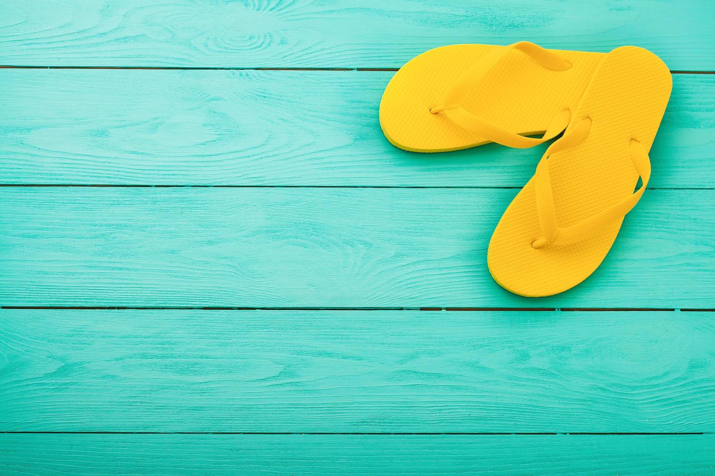 gelbe Flip-Flops auf blauem Hintergrund aus Holz. Sommer Strandurlaub. Ansicht von oben. Attrappe, Lehrmodell, Simulation. Platz kopieren foto