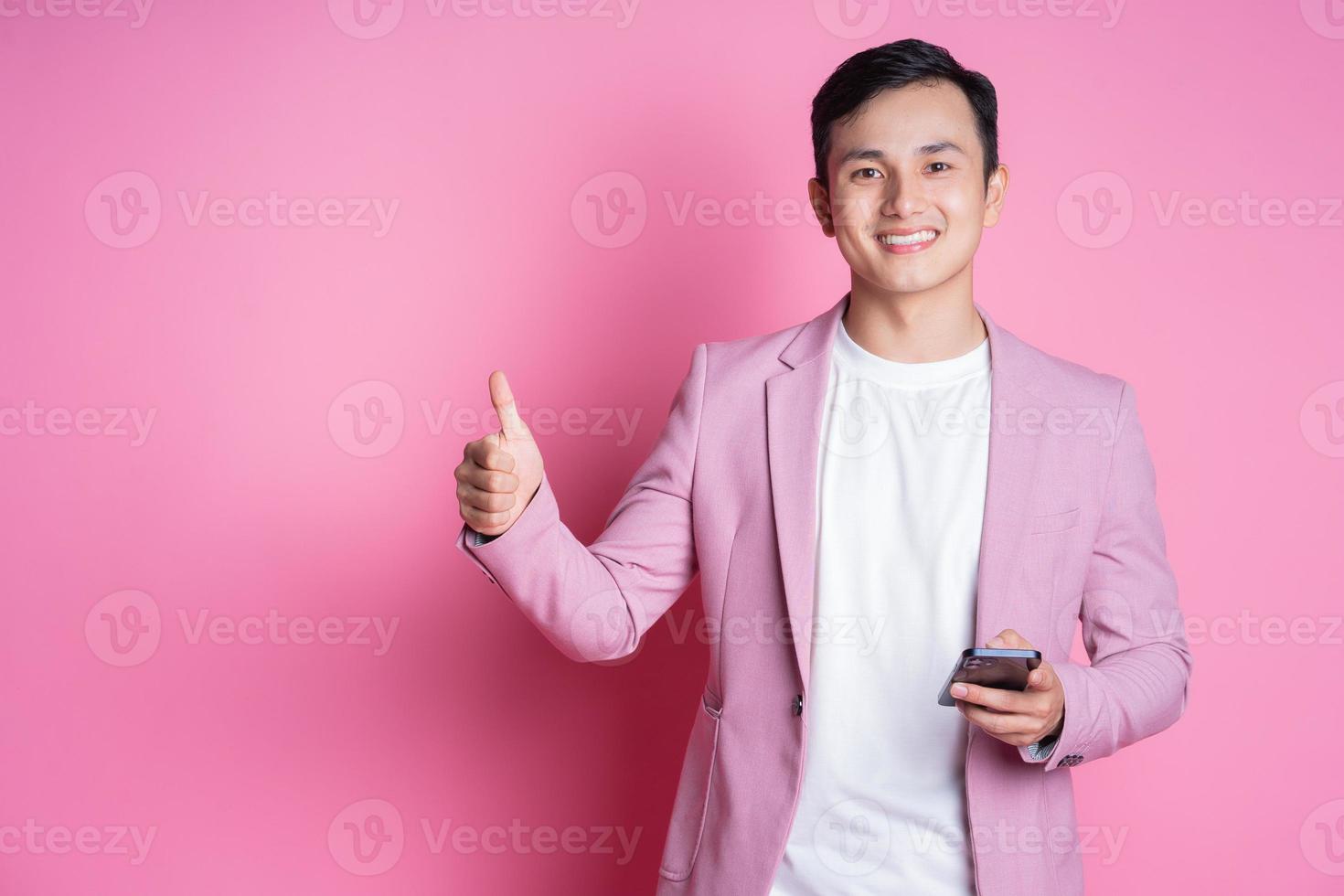 Porträt eines jungen asiatischen Mannes mit rosafarbenem Anzug, der im Hintergrund posiert foto