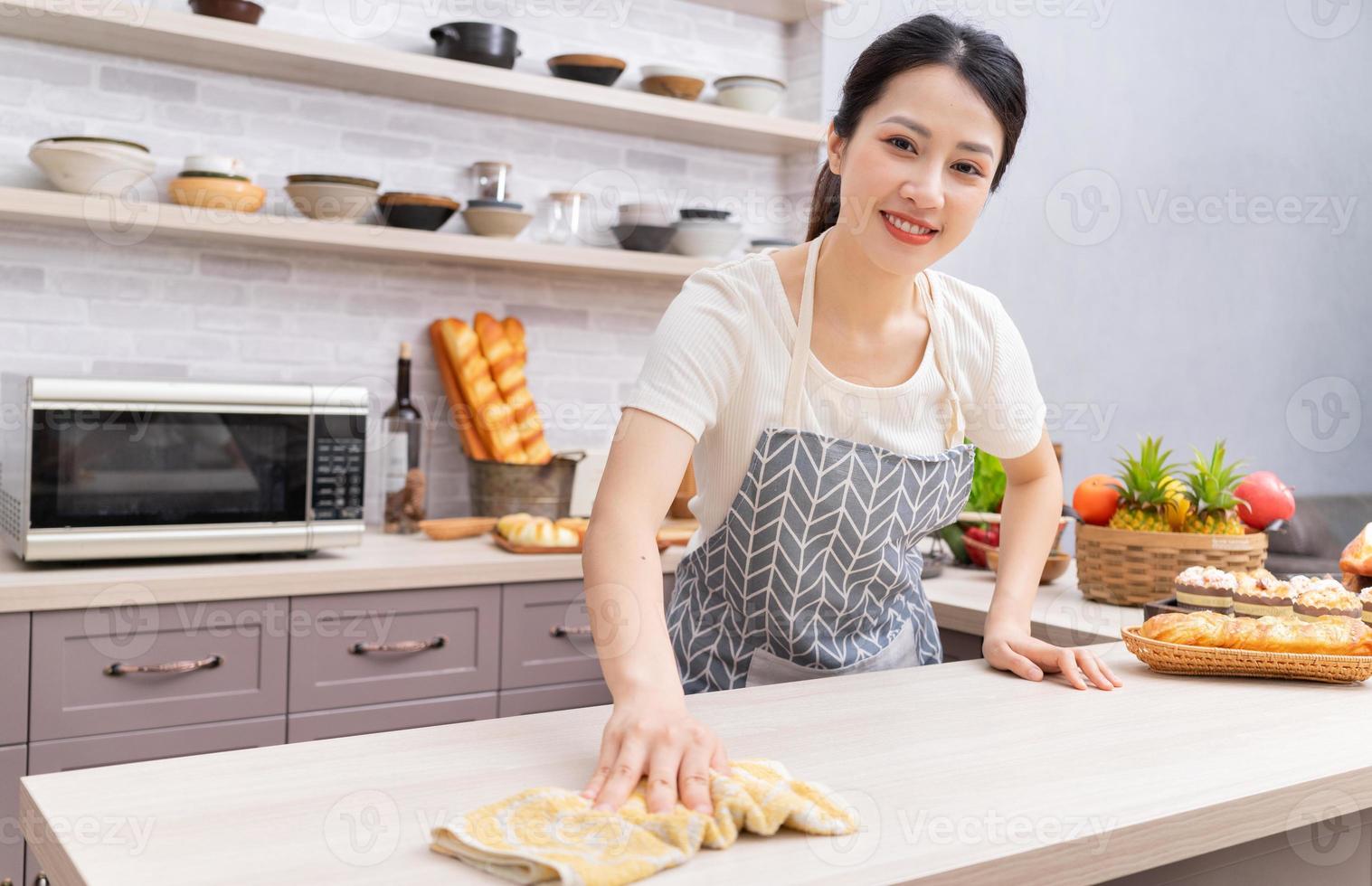 junge asiatische frau, die die küche nach dem kochen reinigt foto