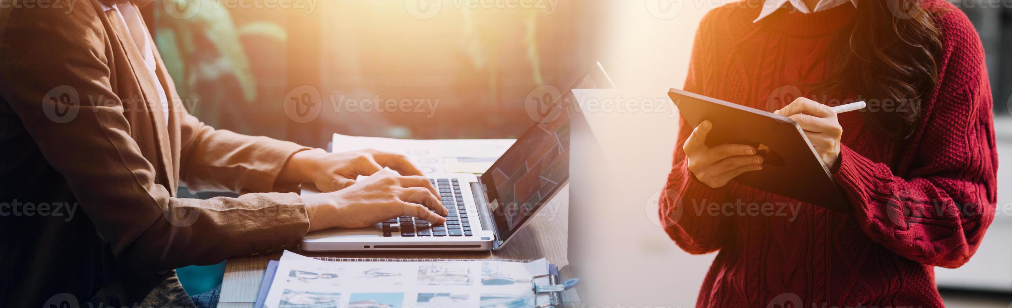 volle Konzentration bei der Arbeit. Gruppe junger Geschäftsleute, die zusammen mit im Hintergrund sitzenden Kollegen am Schreibtisch arbeiten und kommunizieren foto