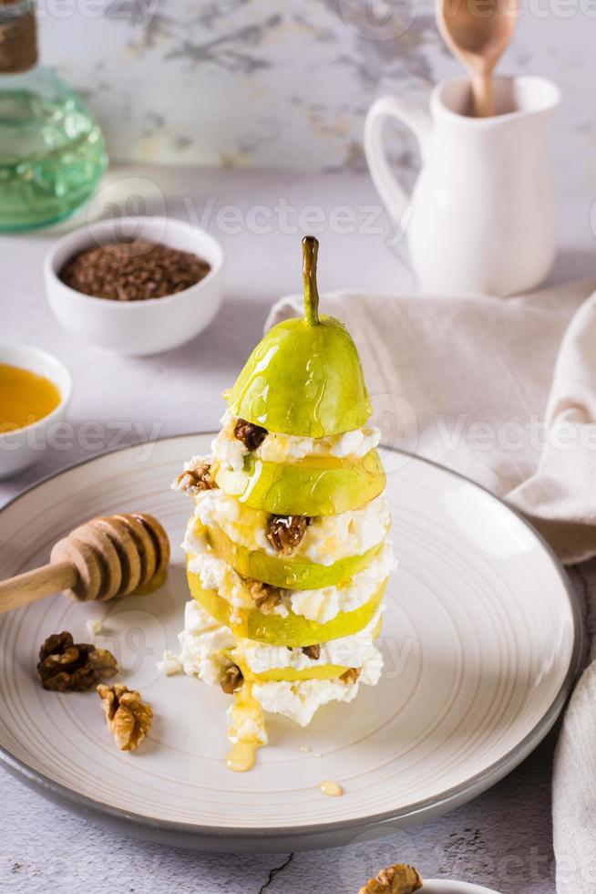 Birnenschichten, Ricotta mit Walnuss, gegossen mit Honig auf einem Teller. vitamin ernährung. vertikale Ansicht foto