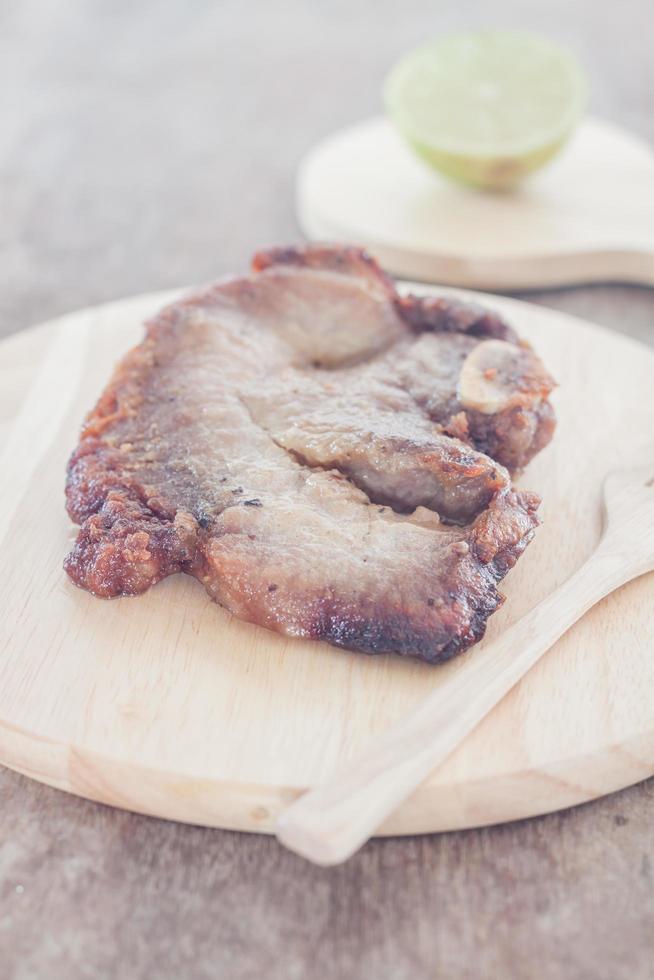 Schweinesteak und eine Limette auf einem Teller foto